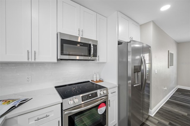 kitchen with decorative backsplash, white cabinets, appliances with stainless steel finishes, light stone countertops, and dark hardwood / wood-style floors