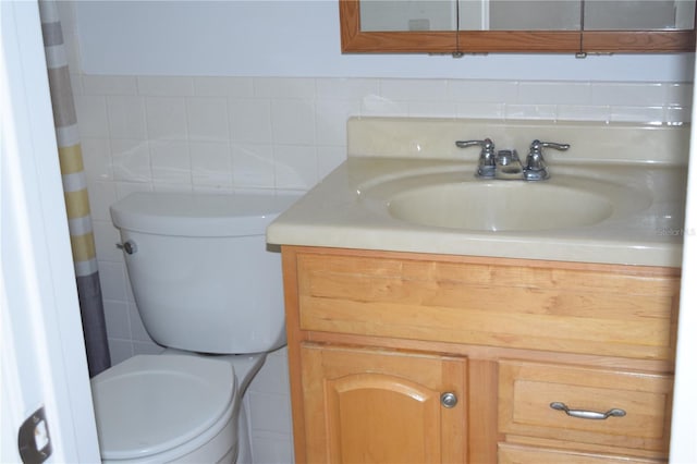 bathroom with vanity, tile walls, and toilet