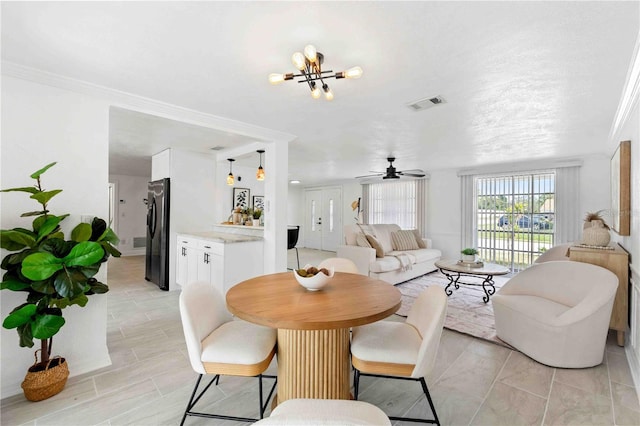 dining area featuring ceiling fan with notable chandelier and ornamental molding