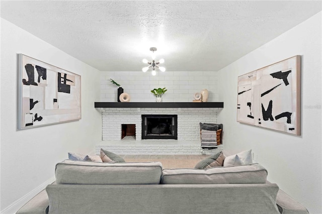 living room featuring an inviting chandelier, a textured ceiling, and a brick fireplace