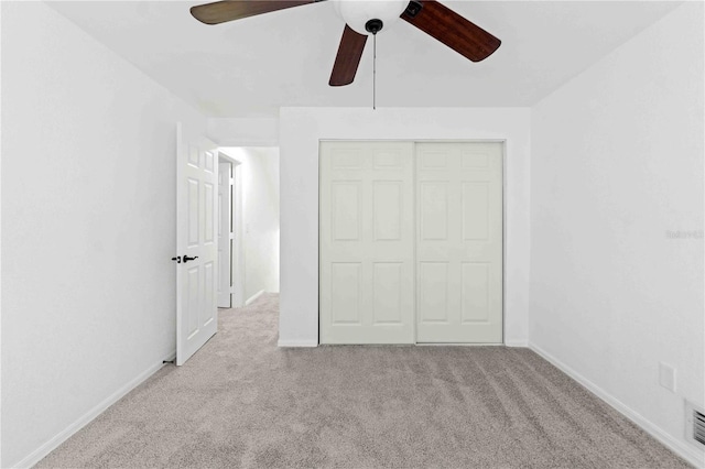 unfurnished bedroom featuring light carpet, ceiling fan, and a closet