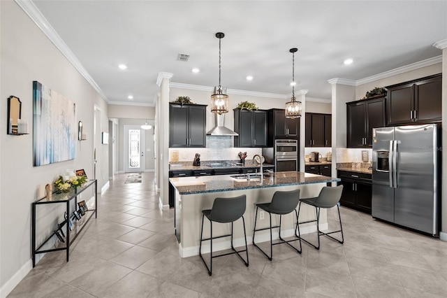 kitchen with appliances with stainless steel finishes, a center island with sink, ornamental molding, and sink