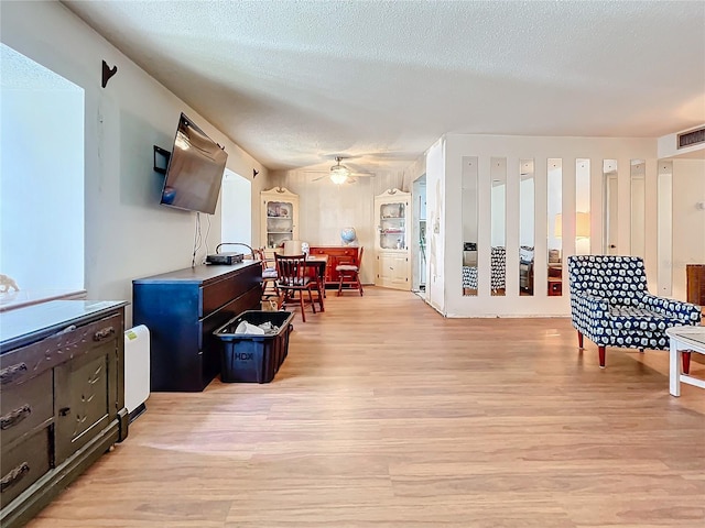 interior space with light hardwood / wood-style flooring, ceiling fan, and a textured ceiling