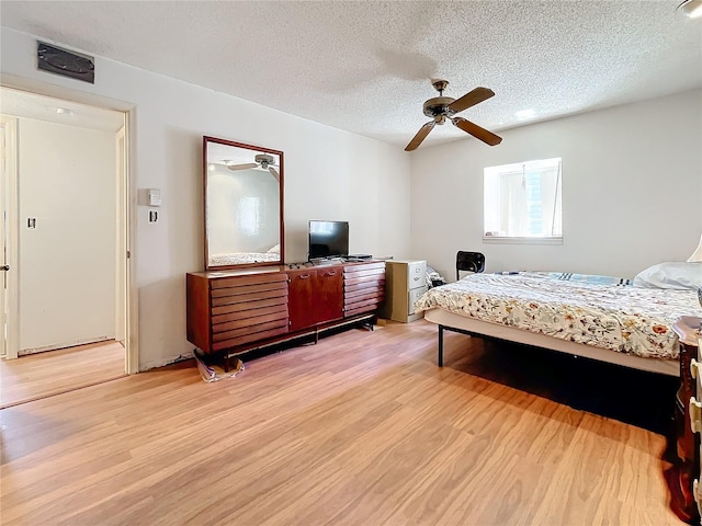 bedroom featuring light wood-type flooring, ceiling fan, and a textured ceiling