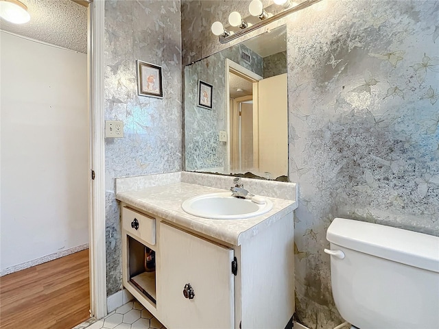 bathroom featuring a textured ceiling, wood-type flooring, vanity, and toilet