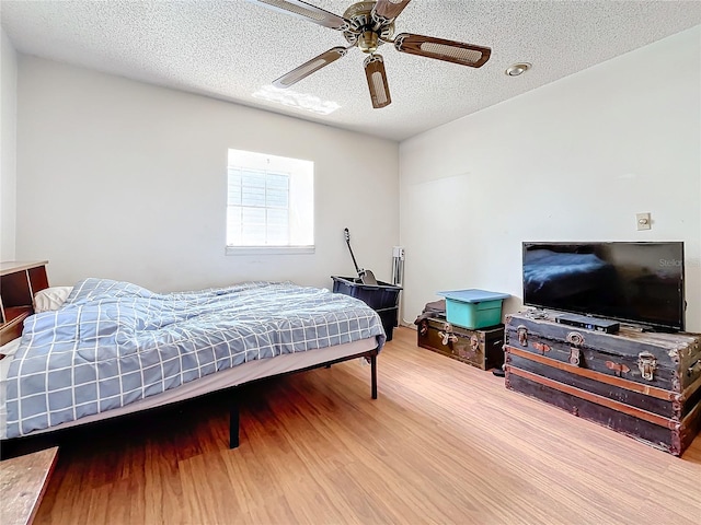 bedroom featuring ceiling fan, hardwood / wood-style floors, and a textured ceiling