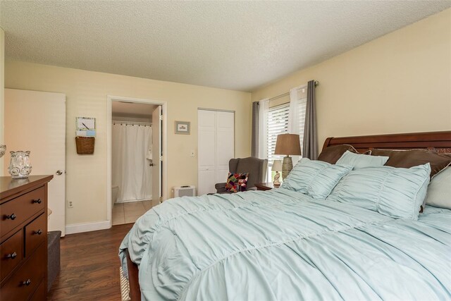 bedroom with dark wood-type flooring, a closet, ensuite bathroom, and a textured ceiling