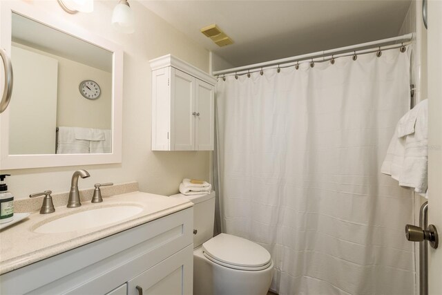 bathroom featuring vanity, curtained shower, and toilet