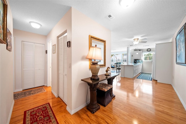 hall with a textured ceiling and light hardwood / wood-style floors