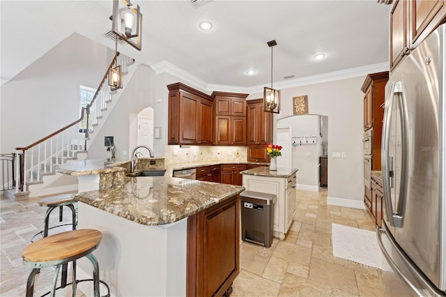 kitchen featuring arched walkways, appliances with stainless steel finishes, a peninsula, stone tile flooring, and a sink