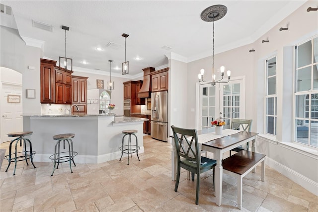 interior space featuring decorative backsplash, appliances with stainless steel finishes, a breakfast bar area, a peninsula, and hanging light fixtures