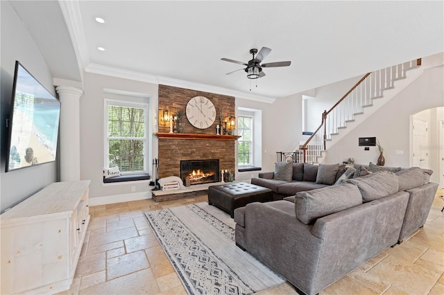 living room featuring stone tile floors, recessed lighting, ornamental molding, a stone fireplace, and baseboards