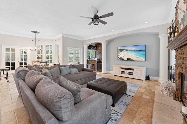 living area featuring stone tile flooring, decorative columns, a stone fireplace, and baseboards