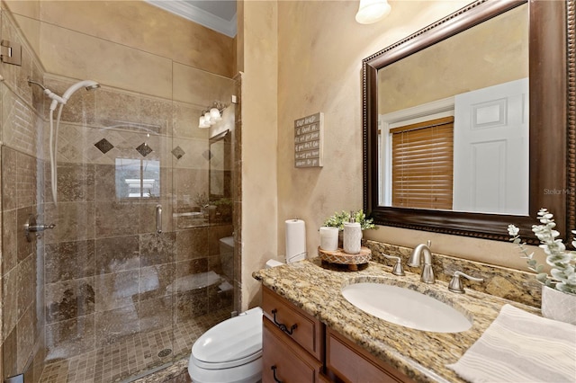 bathroom with toilet, a shower stall, vanity, and crown molding