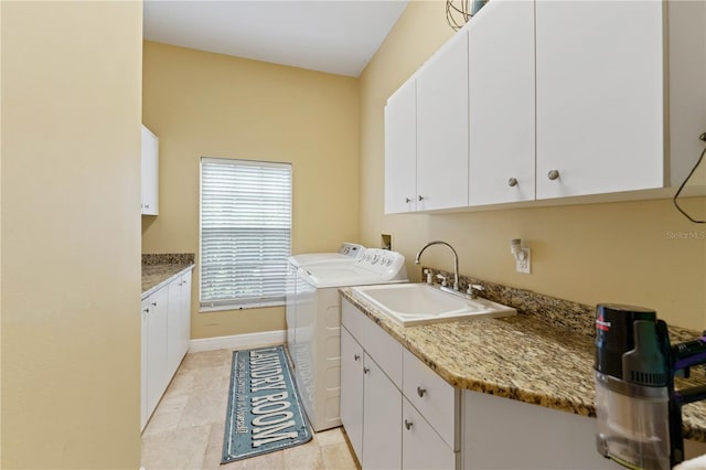 laundry area with cabinet space, baseboards, a sink, and washing machine and clothes dryer