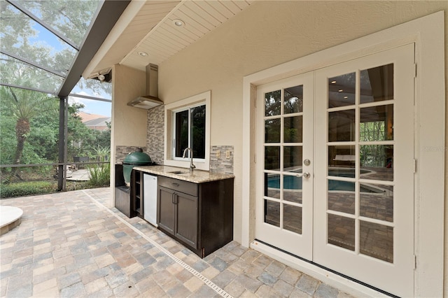 view of patio / terrace with glass enclosure, area for grilling, a sink, exterior kitchen, and french doors