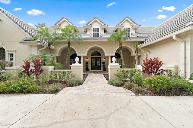 view of front of house with a tiled roof, french doors, and stucco siding