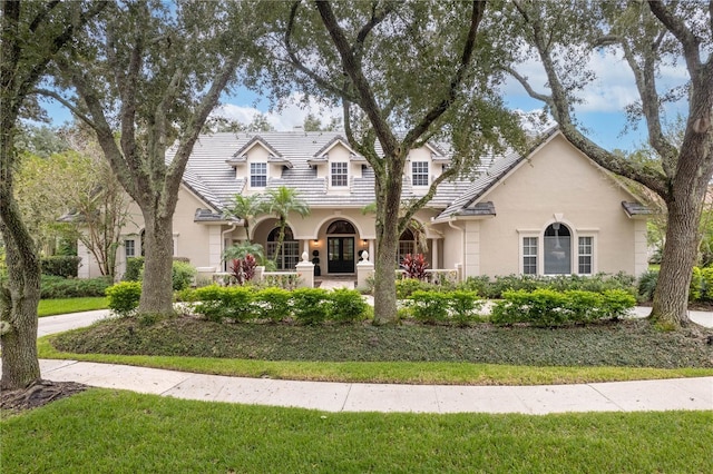 view of front of property with stucco siding, a front yard, and a tiled roof