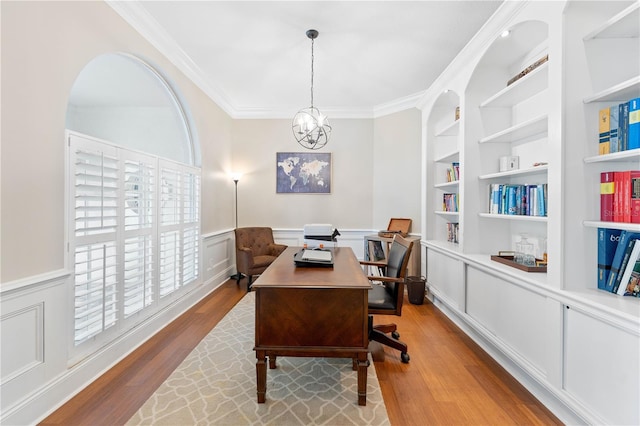 home office with wainscoting, ornamental molding, wood finished floors, an inviting chandelier, and built in shelves