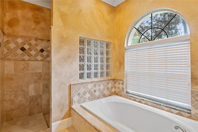 full bathroom featuring walk in shower, a bath, and a textured wall