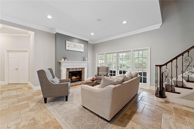 living area featuring baseboards, stairs, crown molding, stone tile flooring, and a brick fireplace