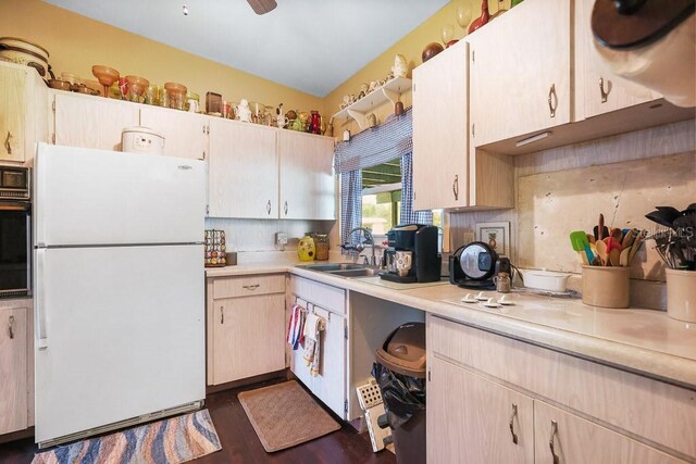kitchen featuring light countertops, tasteful backsplash, oven, a sink, and freestanding refrigerator