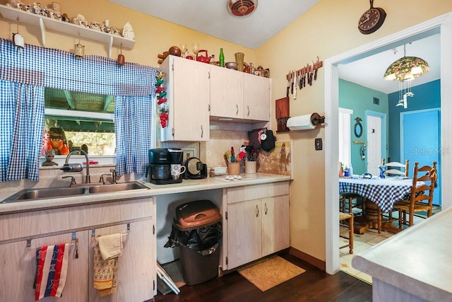 kitchen featuring light countertops, decorative backsplash, dark wood finished floors, a sink, and visible vents