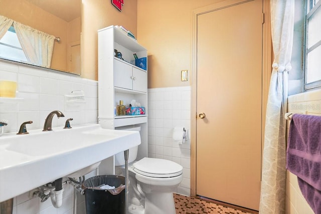 bathroom featuring tile walls, a wainscoted wall, and toilet