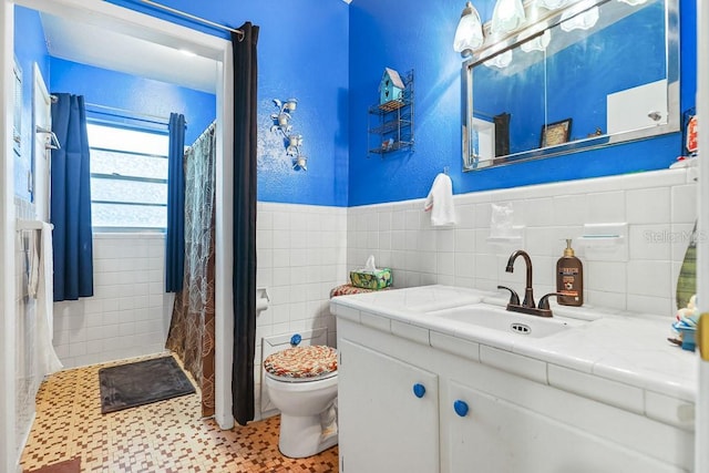 bathroom with tile walls, curtained shower, vanity, and toilet