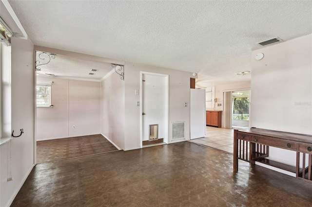 spare room with a textured ceiling, concrete floors, and a wealth of natural light