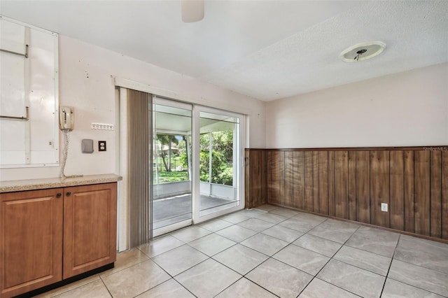 tiled spare room featuring a textured ceiling and wood walls