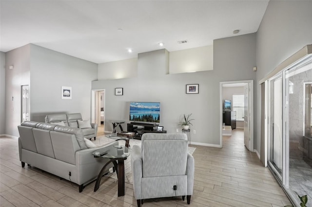 living room with a towering ceiling and light hardwood / wood-style floors