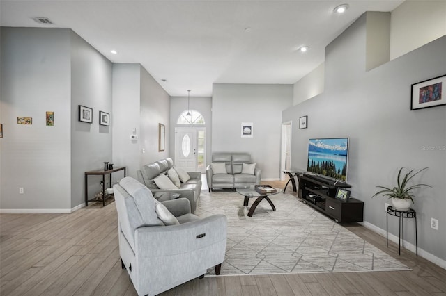 living room with light wood-type flooring and a high ceiling