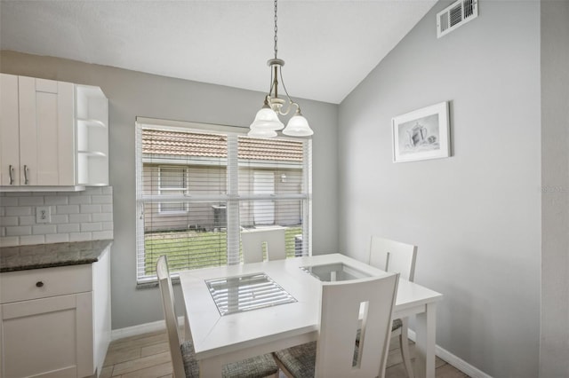 dining area with vaulted ceiling, a chandelier, light hardwood / wood-style flooring, and a wealth of natural light