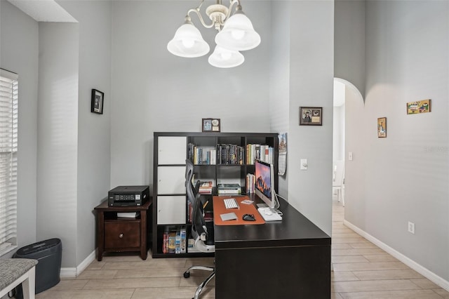 home office featuring an inviting chandelier, light wood-type flooring, and a high ceiling