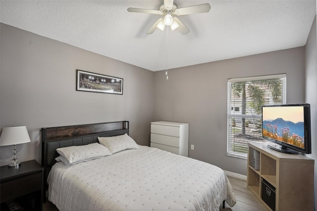 bedroom with ceiling fan, a textured ceiling, and light wood-type flooring