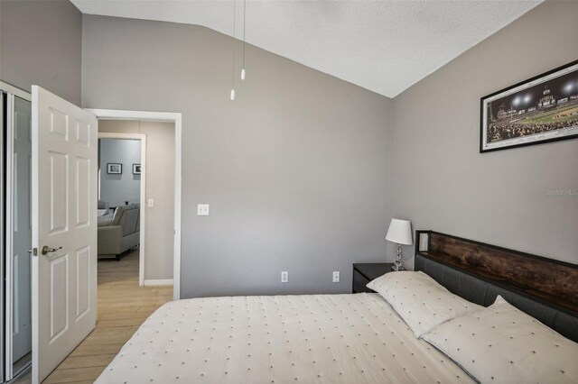 bedroom with light hardwood / wood-style flooring and high vaulted ceiling