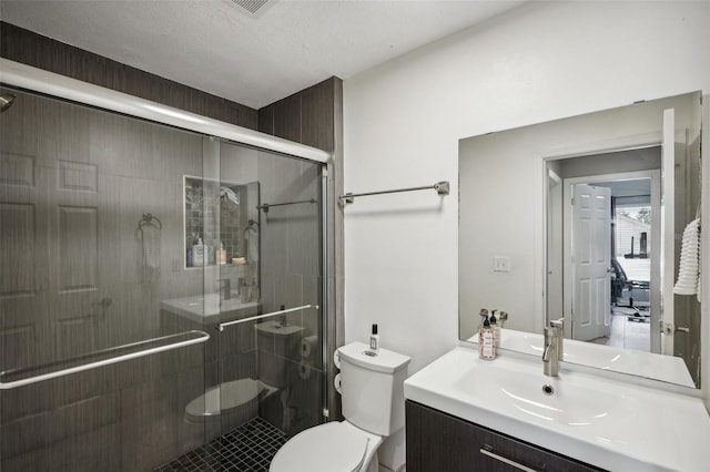 bathroom featuring a textured ceiling, walk in shower, vanity, and toilet