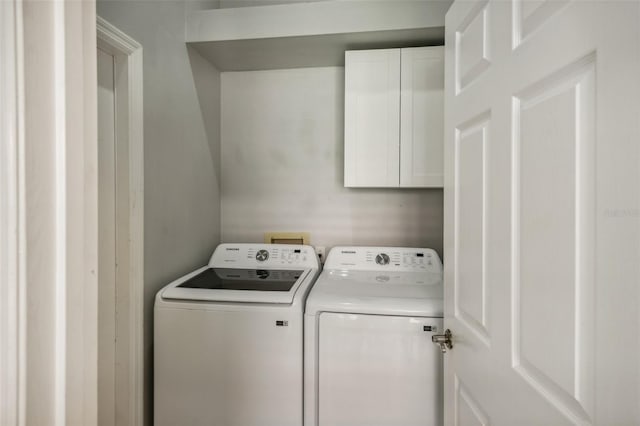 clothes washing area with cabinets and washer and clothes dryer