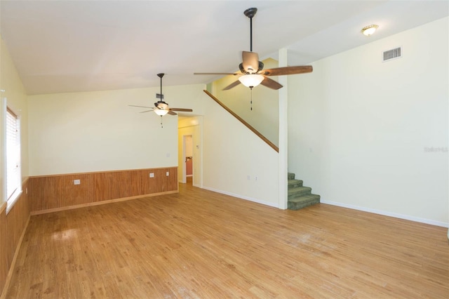 interior space featuring lofted ceiling, wood walls, ceiling fan, and light hardwood / wood-style flooring