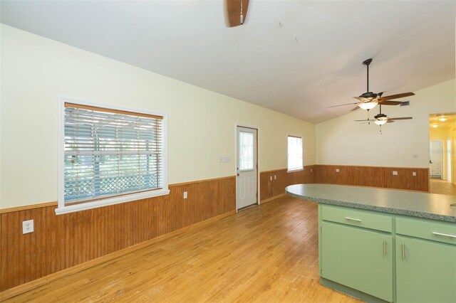 interior space featuring lofted ceiling, wood walls, light hardwood / wood-style flooring, green cabinets, and ceiling fan