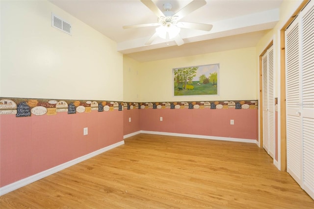 empty room with ceiling fan and light hardwood / wood-style flooring