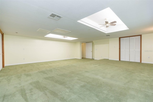 carpeted empty room with ceiling fan and a skylight