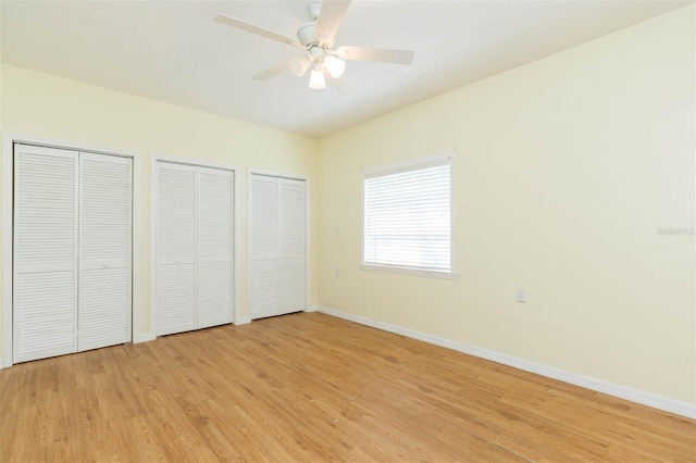 unfurnished bedroom featuring light wood-type flooring, two closets, and ceiling fan