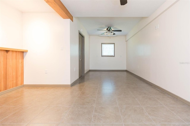 empty room featuring ceiling fan, beamed ceiling, and light tile patterned flooring