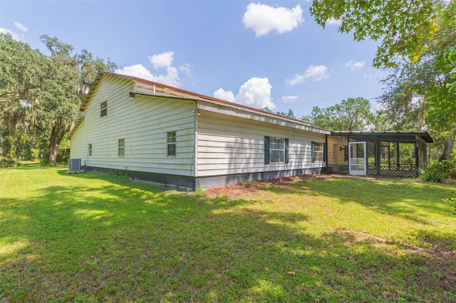 exterior space featuring a lawn, a sunroom, and central air condition unit