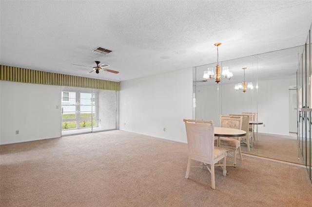 carpeted dining room with a textured ceiling and ceiling fan with notable chandelier