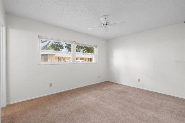 spare room with ceiling fan, a textured ceiling, and light carpet