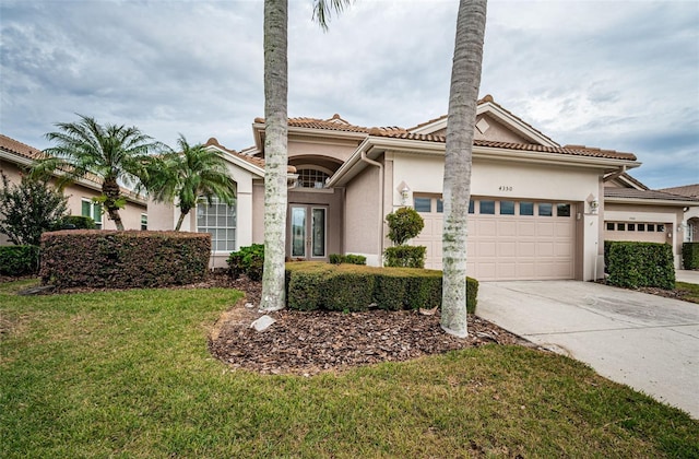 mediterranean / spanish house featuring a garage, a tile roof, concrete driveway, stucco siding, and a front lawn