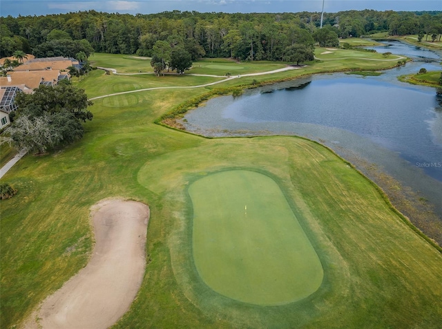 drone / aerial view featuring a water view, a wooded view, and golf course view